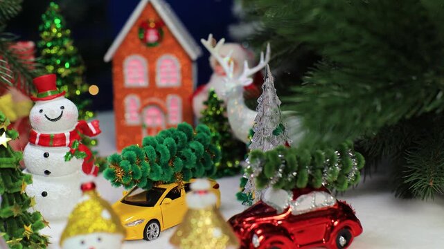 In front of the orange house there are snowmen with Christmas trees and cars