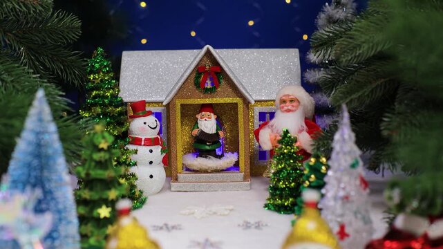 In front of the house with a gnome on the porch and a snowman with Santa Claus on the sides there are many Christmas trees