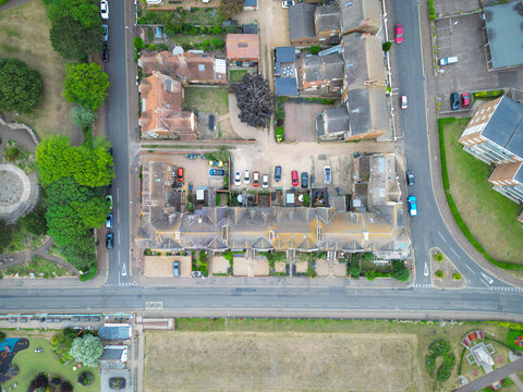 Dramatic top down view of seaside terraced townhouses seen overlooking a parched green in the victorian-era town of Hunstanton, Norfolk, UK. The houses overlook the sea.