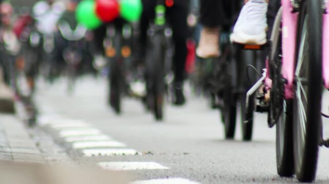 Low angle view of cyclists riding bicycles on street during group bike event, showing movement of wheels and legs, creating dynamic visual of communal activity