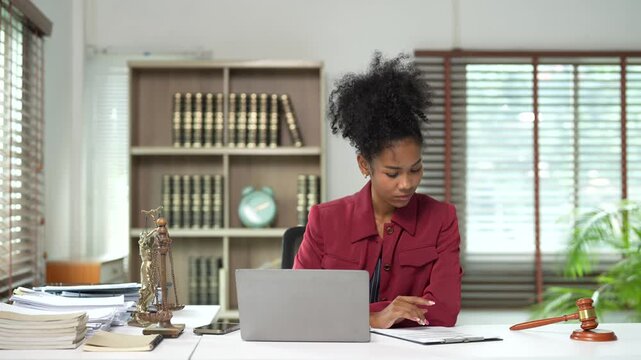 African american female lawyer or business woman working at a law firm office desk with laptop and gavel, providing legal advice, notary, and justice services