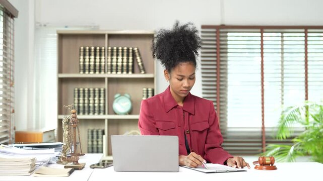 African American female lawyer working on a legal case, studying documents, and providing justice and consultation services in a modern courtroom or office setting