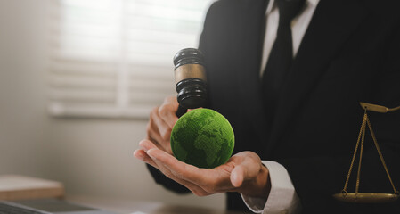 Judge's gavel striking a green Earth symbol, representing environmental law, climate justice, sustainability regulations, and global governance. © Natthawadee