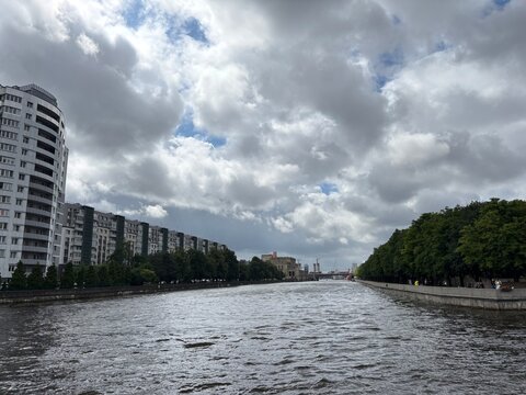 City river with cloudy sky and urban buildings along the bank  