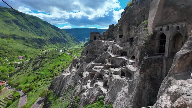 Panoramic view of the vardzia cave monastery complex, a historic cultural monument carved into the slopes of the erusheti mountain in southern georgia, with tourists visiting the site