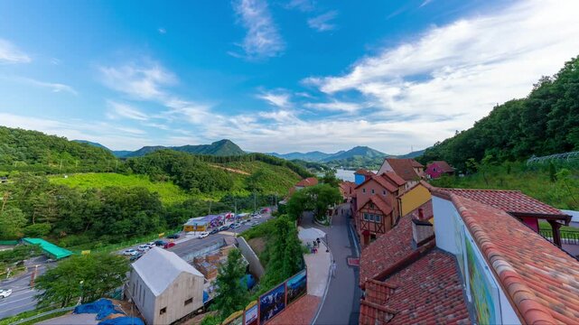 Daytime timelapse of Petite France cultural village in Gapyeong, featuring colorful European style houses and French architecture under a bright blue sky with moving clouds, South Korea.