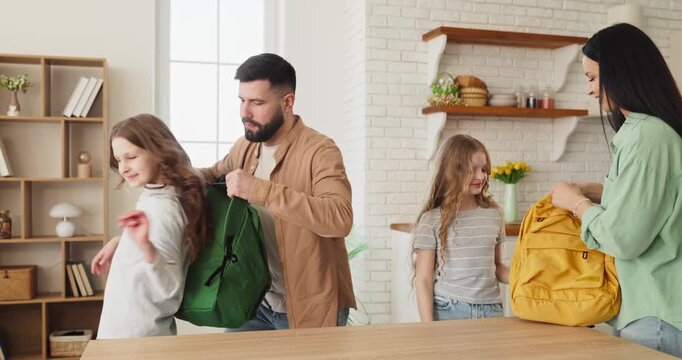 Family parents children mother father girls packing. Home kitchen morning as parents help kids packing school backpacks organizing supplies before leaving. Clear family school morning concept.