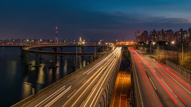Twilight cityscape timelapse of Seoul highway traffic light trails along the Han River, panoramic view of Gangbyeonbuk-ro expressway and Lotte World Tower in South Korea.