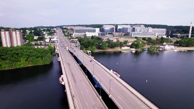 Aerial flight over the Kenneth F Burns bridge facing the city of Worcester. Early morning traffic speeds along both directions of the bridge and Lake Quinsigamond can be seen below.