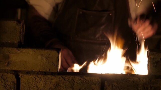 Hands tending a glowing forge fire in a workshop, sparks rising in low light