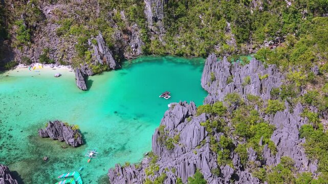 Aerial drone view of Cadlao Lagoon in El Nido, Palawan, Philippines, with turquoise water, limestone cliffs, and boats in a secluded tropical paradise.