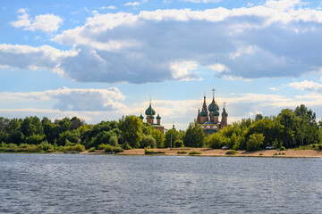 View of the sandy shore of the Volga River with a forest and a medieval church with green domes in Yaroslavl, Russia © Sergey