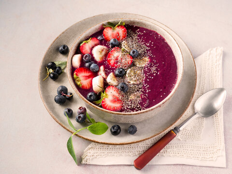 Smoothie bowl made from homegrown blueberries topped with strawbery, banana, and chia seed; copy space