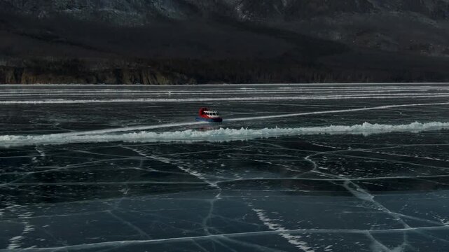 Vibrant Red hovercraft Swiftly Moves Across Icy Black Lake Capturing Dynamic Motion Expertly