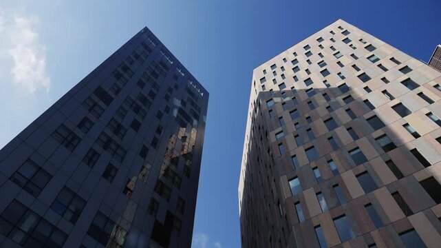 Modern glass office scyscraper buildings beautifully reflecting the clear blue sky in an urban environment