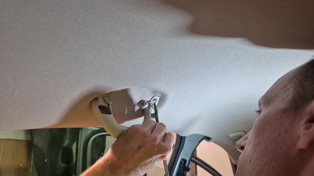Car repair maintenance man removing overhead grab handle in vehicle interior during automotive DIY project
