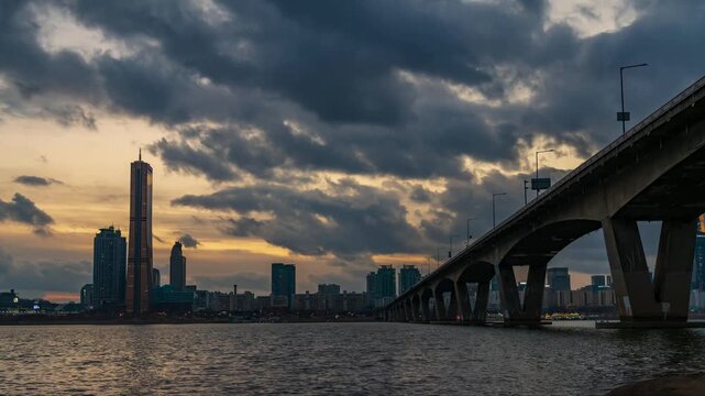 Sunset timelapse of the iconic 63 Building and Wonhyo Bridge over the Han River in Yeouido district, scenic cityscape skyline under dramatic storm clouds in Seoul, South Korea.