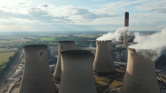 Power Station Cooling Towers Emitting Steam Into a Cloudy Sky at Daytime