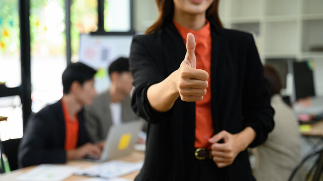 Cropped of Business Owner Giving Thumbs Up in Front of Team Meeting at Modern Office