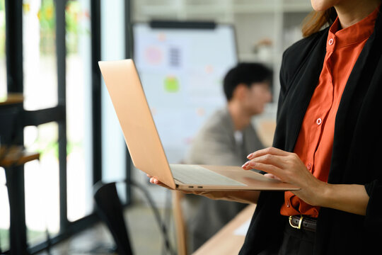 Close Up of Businesswoman Holding Notebook Laptop During Office Seminar Presentation with Whiteboard in Background