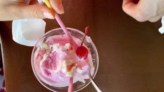  Top Angle Close Up of Strawberry Ice Cream Sundae with Cherry and Hand