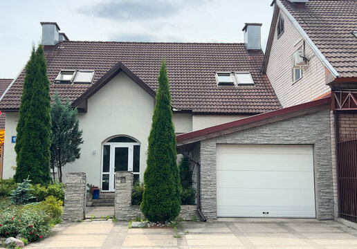 Modern townhouse with private garage, landscaped entrance and evergreen trees in a quiet suburban residential neighborhood