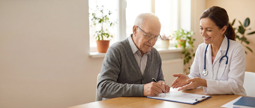 Senior patient signs treatment authorization documents while compassionate physician explains paperwork in bright private consultation room, conveying trust, informed consent and quality healthcare.