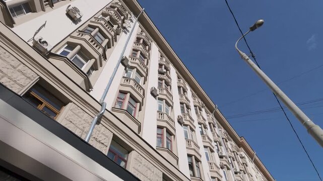 Wide upward view of classic residential apartment buildings with bay windows and ornate cornices under a clear blue sky