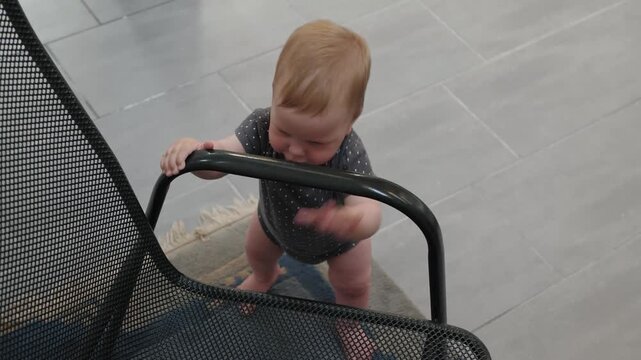 Infant tries standing. Toddler tests their ability to stand on various furniture items. Small child intentionally explores and challenges their balance on different household furniture surfaces