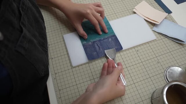 Hands glue dark green leather patch onto white card backing