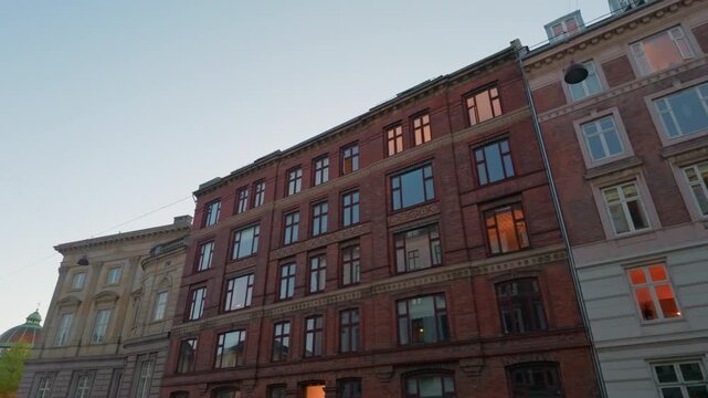 Brick buildings facade sunset street, gimbal stabilizer shot. 60fps tracking view looking up at white and red architecture block in Copenhagen Denmark.