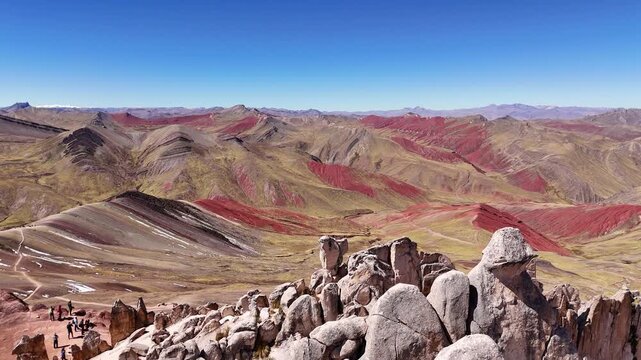 An upward rising aerial view revealing the striking mineral-striped ridges and vast colorful valleys of Palccoyo Rainbow Mountain in Peru