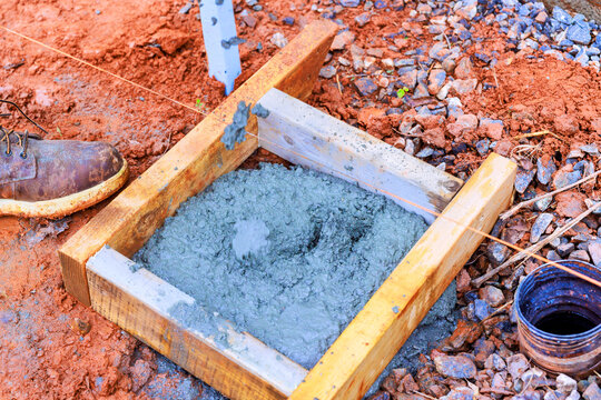 Worker mixes concrete in wooden mold on construction site
