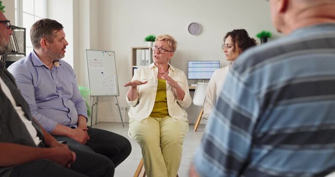Adults with therapist in group therapy circle session. Adults join discussion and receive counseling in a support meeting in a welcoming bright room. Concept of mental health support.