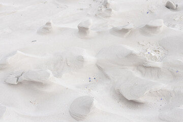 Obraz premium Wind-sculpted sand mounds are forming ripples on dune close-up, showing pebbles and shell fragments