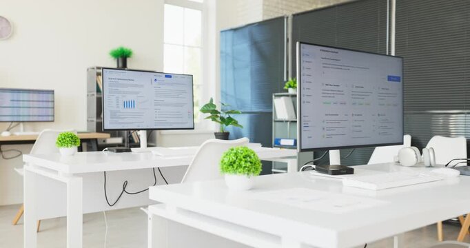 Office computer monitor workspace with spreadsheet data. Minimal office with white desks and modern technology, screens showing tables and charts. Ideal for analysis reporting and finance.