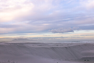 Obraz premium Sand dune is dominating foreground, showing rippled crest and leading to calm shoreline