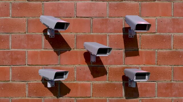 Security cameras mounted on red brick wall, surveillance system for building protection, multiple CCTV monitoring devices in daylight