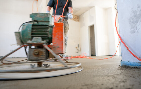 Filling the floor of a renovated apartment with concrete, screed and leveling the floor by construction workers. Even floors made of a mixture of cement, industrial concreting. 
