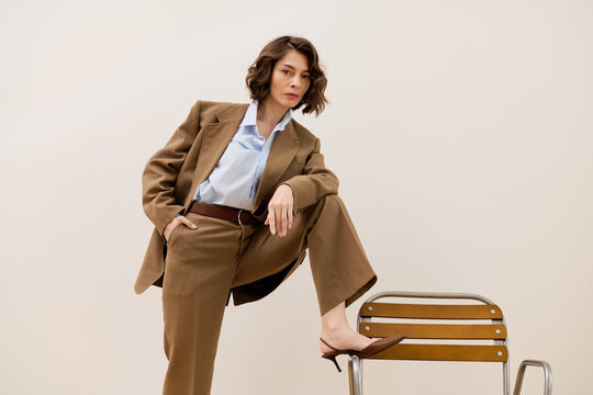 Fashionable woman exudes confidence in elegant attire against a minimalist backdrop