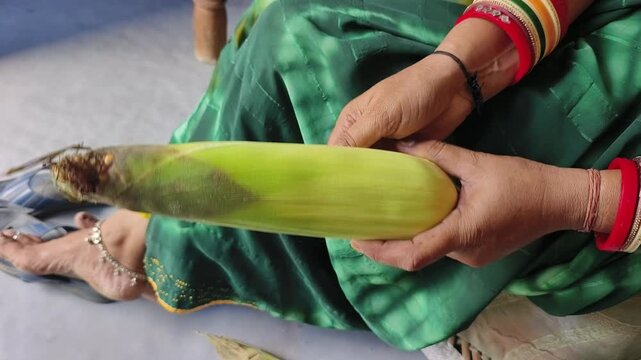 An Indian woman peeling corn cobs