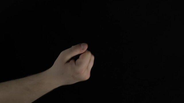 Hand holding a coin ready to flip in a dark room with no distractions