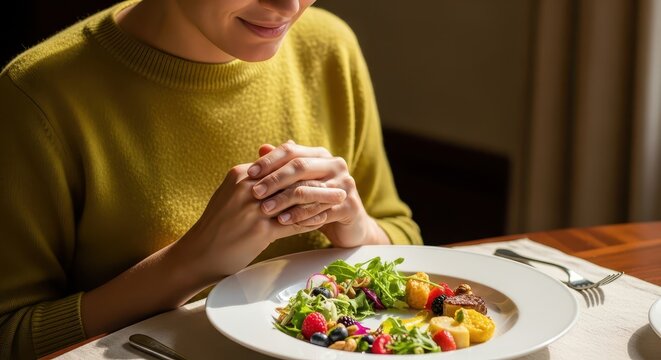 Woman practicing mindful eating with a vibrant salad on a white plate