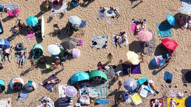 Aerial drone view of a crowded summer lake beach with people swimming and sunbathing. Colorful umbrellas, water obstacle course on lake, on a sunny day. Lake Pogoria in Dabrowa Gornicza, Poland