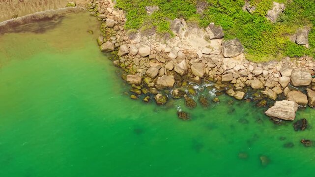 Aerial top down view of a stunning rocky shore with vibrant green water at ayangue beach, ecuador