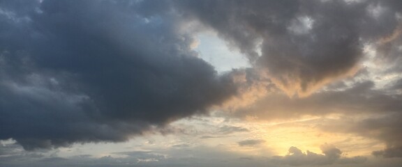 Fototapeta premium Dramatic evening sky with dark monsoon clouds and golden sunset light.