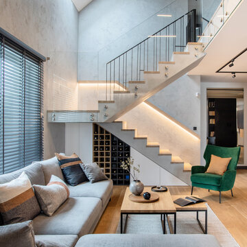 Stylish composition of living room interior with corner grey sofa, green velvet armchair, coffee table, wooden floor,  design furniture and minimalist personal accessories. Modern home decor. 