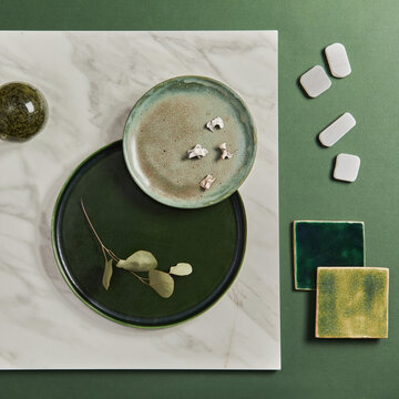 Elegant Green Tableware Arrangement with Natural Accents and Textured Tiles on Marble and Green Surface