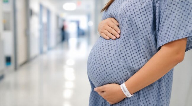 Pregnant woman holding belly in hospital corridor