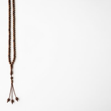 Vertical view of traditional dark brown wooden prayer beads tasbih misbaha isolated on a clean white background with ample copy space for religious or Islamic spiritual design.